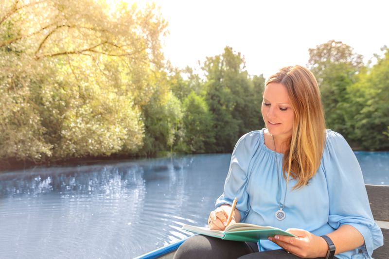 Suki Bluhm schreibt in ihr Notizbuch, während sie im Ruderboot sitzt